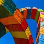 Multicolour shipping containers looping overhead with blue sky background