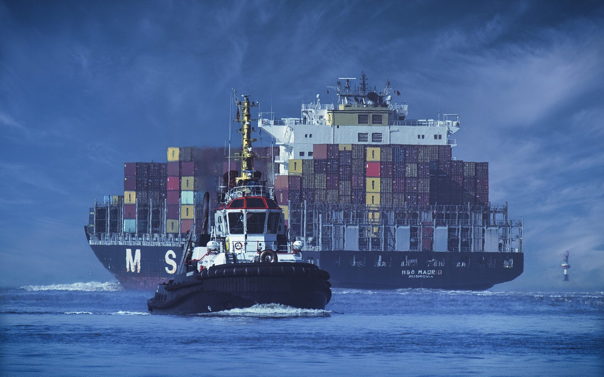 Container ship with tugboat in the foreground