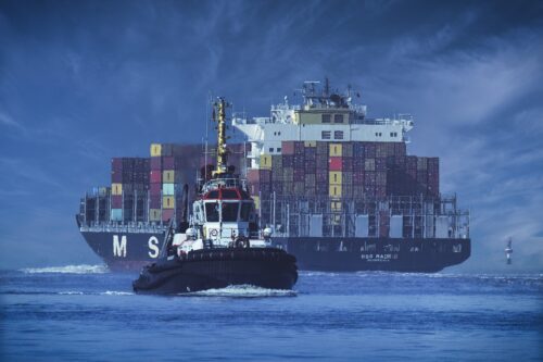 Container ship with tugboat in the foreground